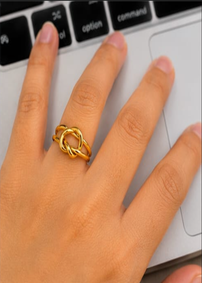 Hand wearing a gold ring with a laptop keyboard in the background