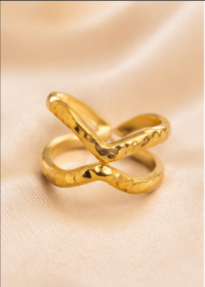 Gold ring with a unique design on a beige fabric background