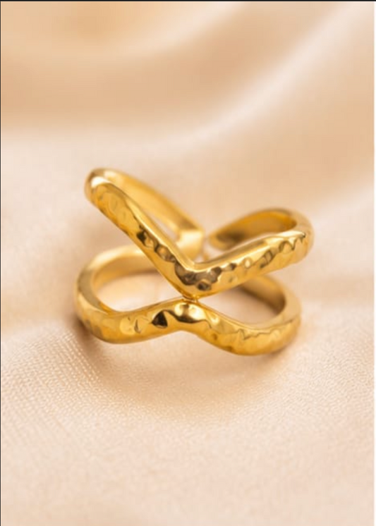Gold ring with a unique design on a beige fabric background